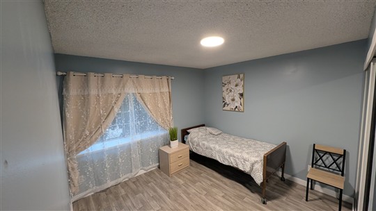 Bedroom with a window, bedside table and floral artwork